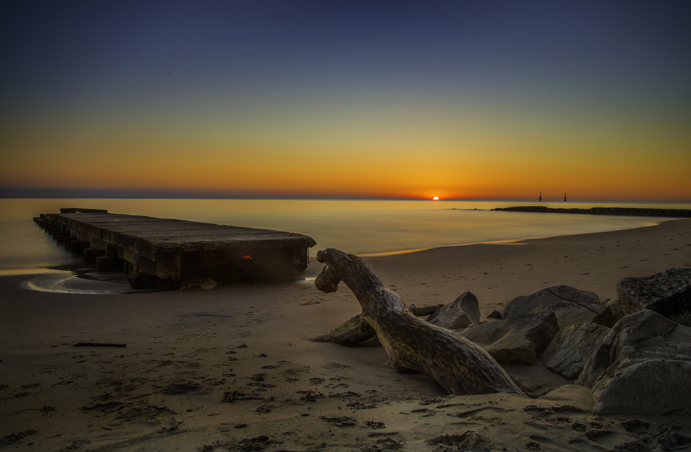 Sunrise over Sheboygan beach with a boardwalk and driftwood in the foreground.
