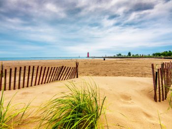 Kenosha Beach with a large stretch of sand and a lighthouse in the background.