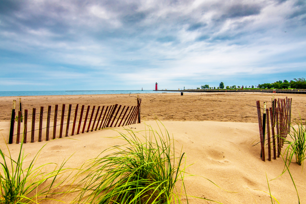 Kenosha Beach with a large stretch of sand and a lighthouse in the background.