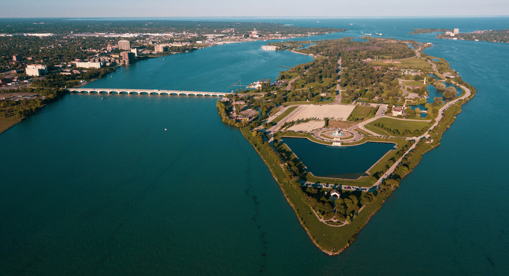 An aerial view of Belle Isle, one of the coolest state parks in Michigan. It is connected to the mainland via a bridge and you can see gardens, a park, and other structures on the island. 