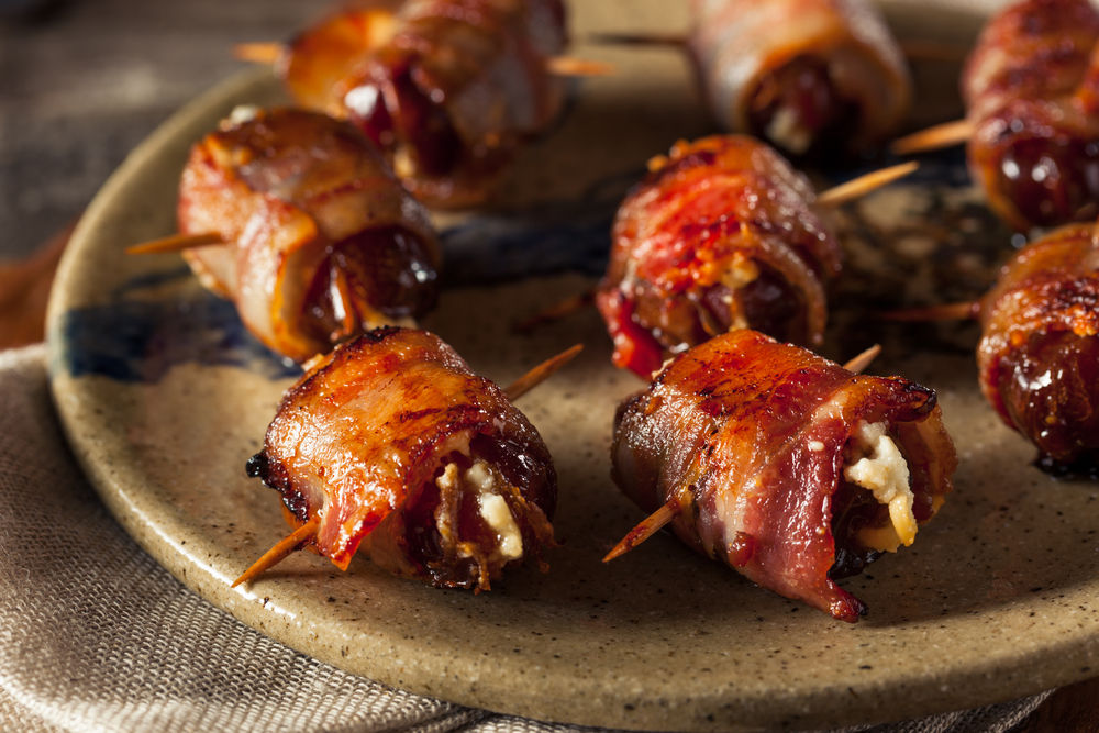 bacon wrapped dates with goat cheese on a plate 