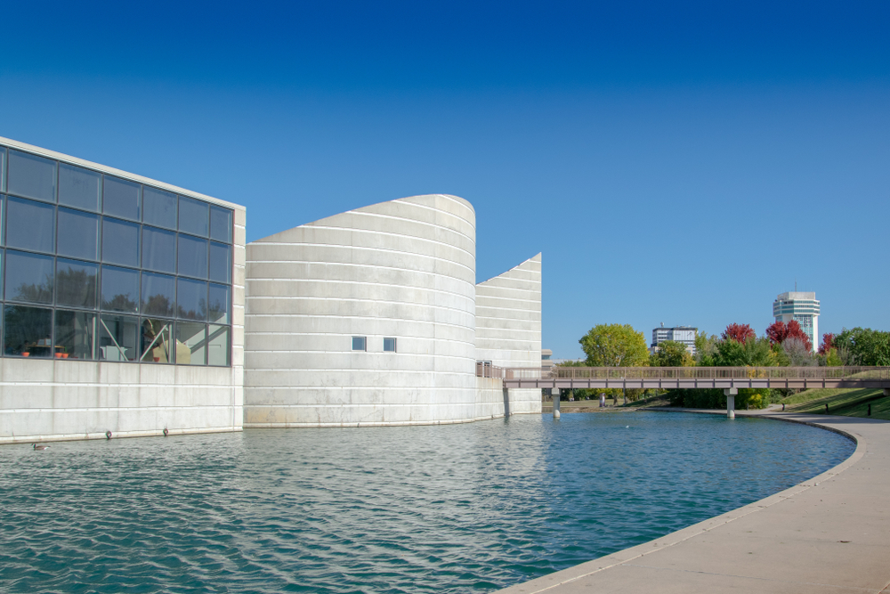 The exterior of the Exploration Place science museum, one of the best things to do in Wichita Kansas. It sits by the river and is a concrete building with interesting angles and large windows in one part of the museum. 