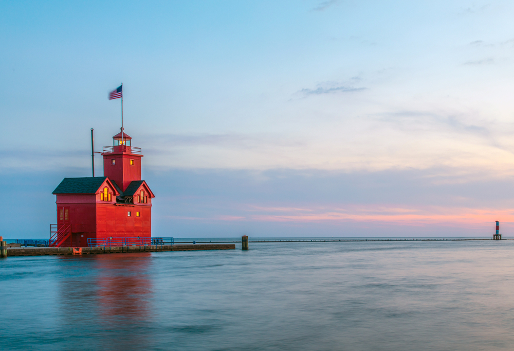 A red Dutch-style lighthouse sitting on a dock at the edge of a calm lake. It's one of the best state parks in Michigan. 