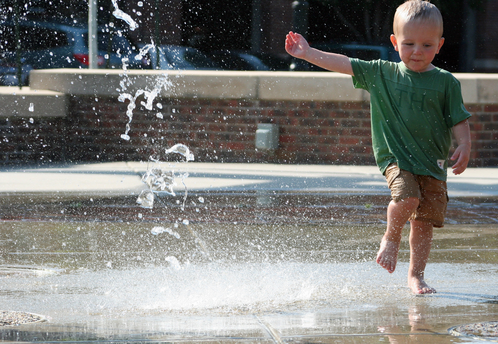 A young child playing in a splash area in a park in Wichita. 