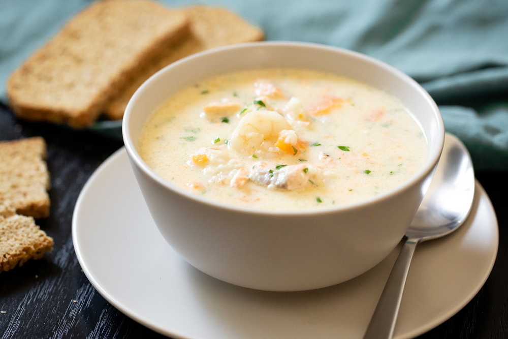 White fish chowder in a bowl with bread to the side 