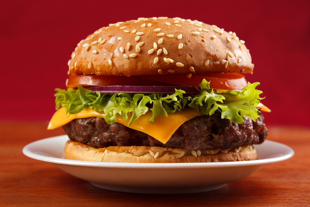 A loaded burger on a plate with a red background in an article about restuarants in Mackinac Islan 
