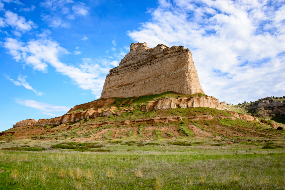 A tall rock formation sticking straight out of the top of a hill. It is surrounded by prairie land and other smaller hills. Its one of the best places to visit in the Midwest. 