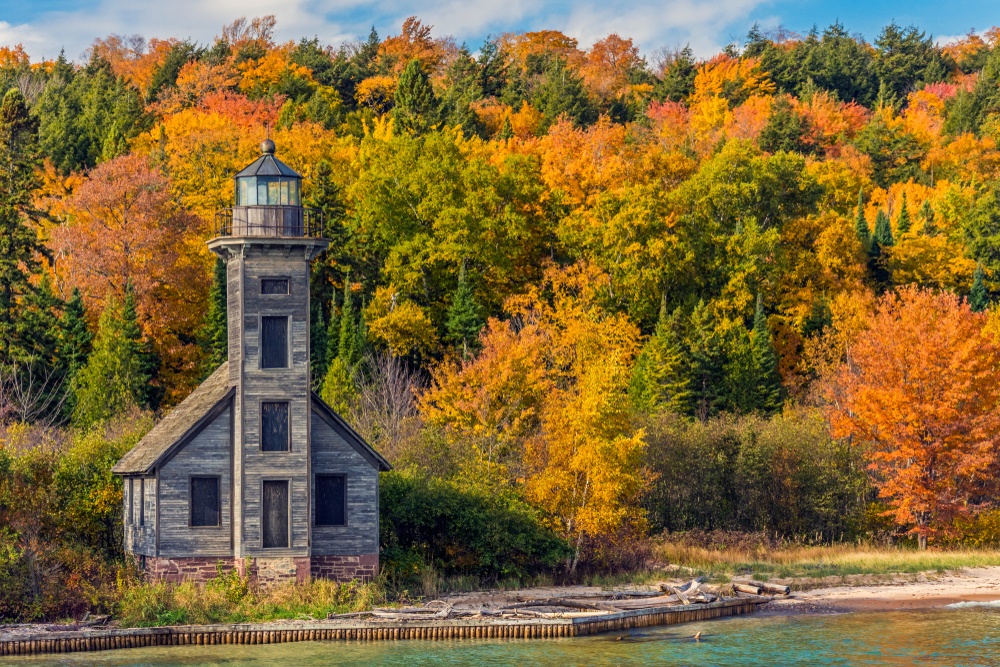 The brown, wooden East Channel Lighthouse surrounded by fiery, fall foliage.