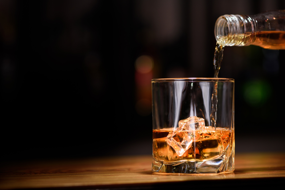 A bottle pouring whiskey into a glass at the Indiana Whiskey Company, one of the best things to do in South Bend, IN.