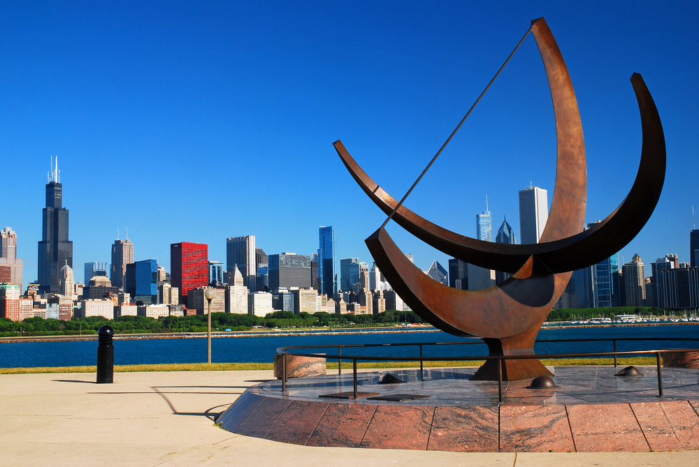 An art sculpture near the lake with the Chicago skyline in the distance.