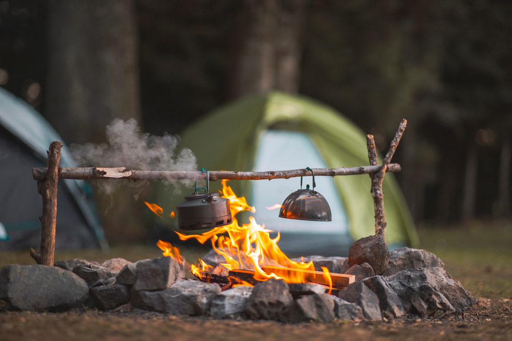 fire burning with a kettle with tent in background camping in nebraska