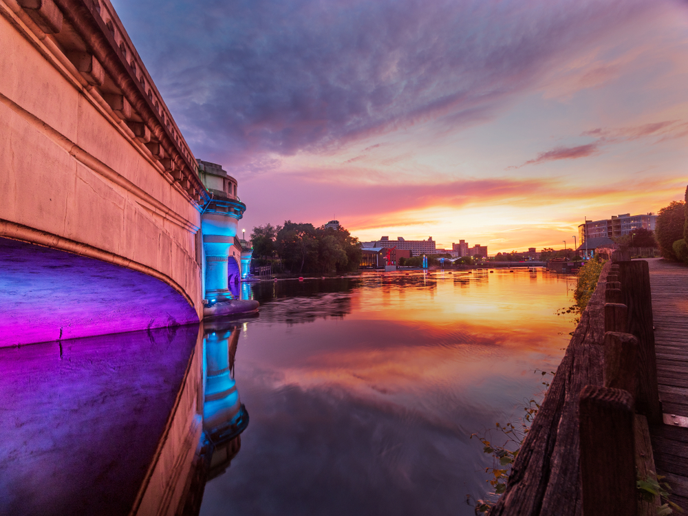 Sunset over the river with the River Lights shining on a bridge.