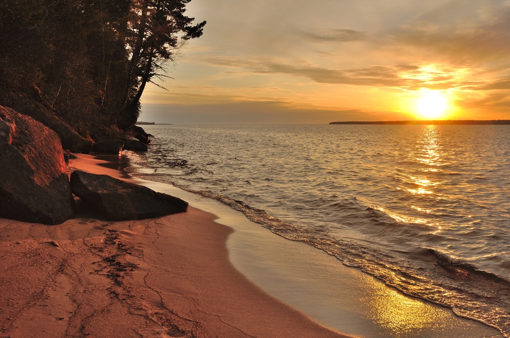 A golden sunset over a sandy beach on the Apostle Islands, some of the best islands in the Midwest.