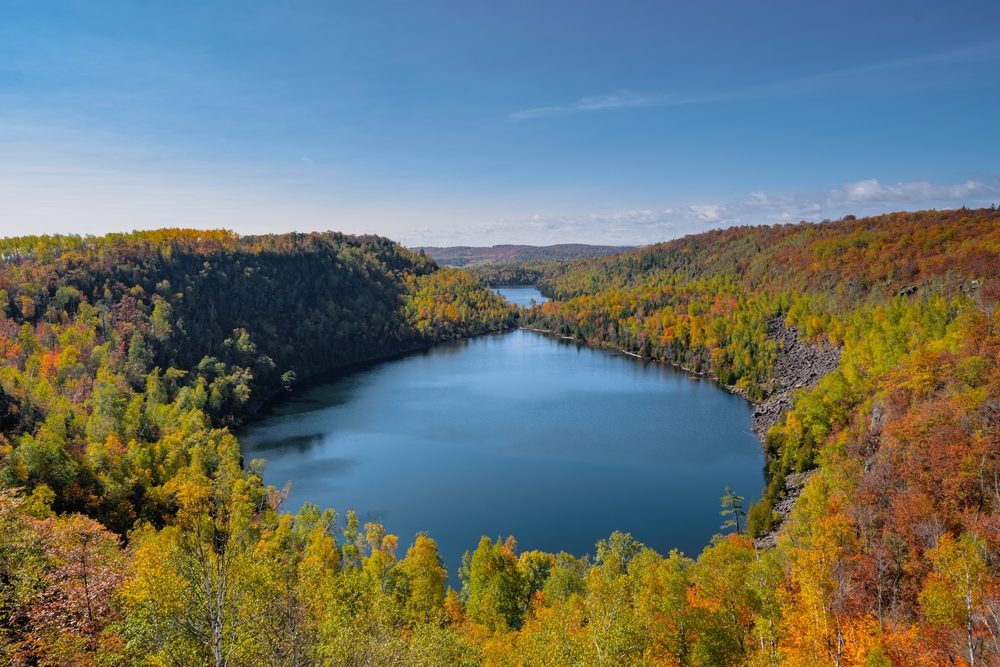 View from above of one of the lakes on the SuperiorTrail surrounded by fall foliage.