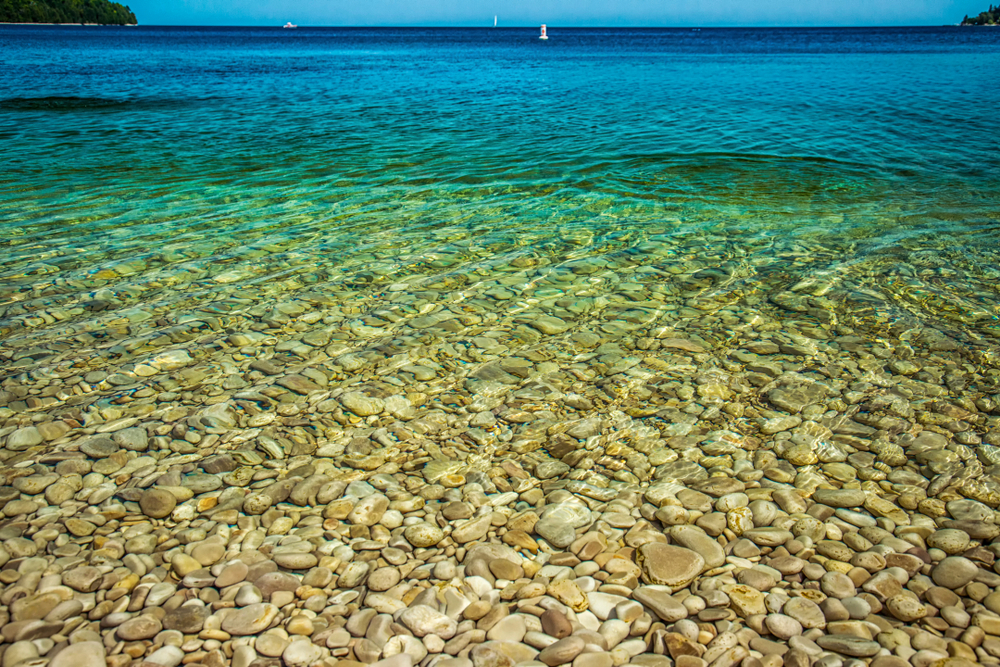 Close-up of the clear, blue water and pebbles at a beach off a Midwest island