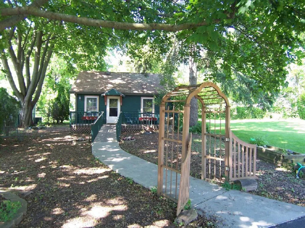 green cabin with a pavement leading to the door through a yard in an article about cabins in Wisconsin 
