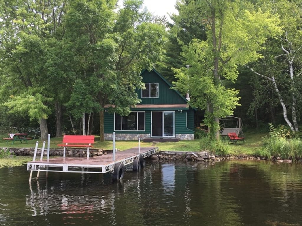 Green cabin by the lake with a deck leading out onto the lake .A great Wisconsin cabin to look into.