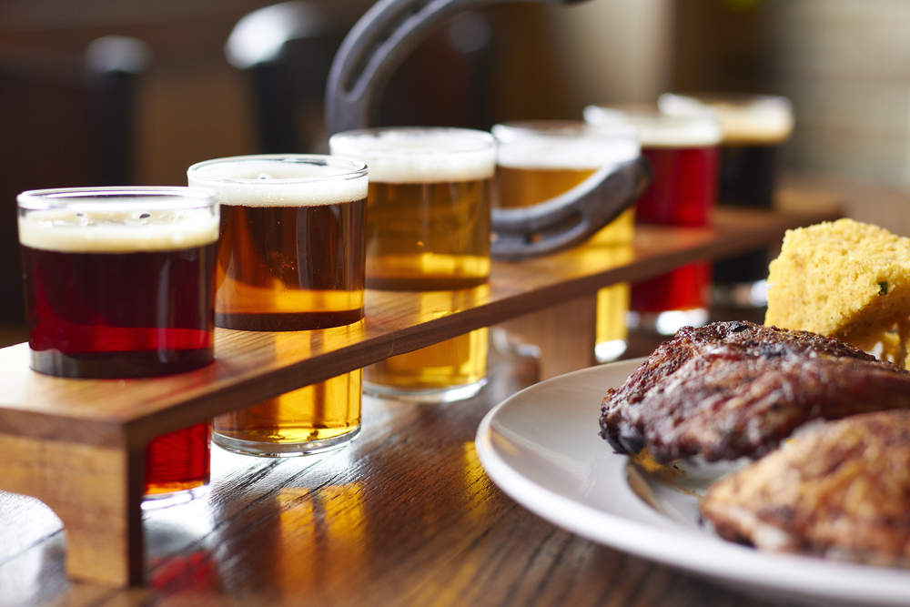 A flight of beer next to a plate of ribs and cornbread. Its similar to meals you can find in restaurants in Topeka.