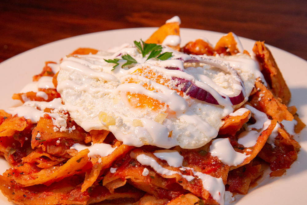 Chilaquiles on a plate in an article about restaurants in Appleton. Tortillas with salsa and an egg on a top. 
