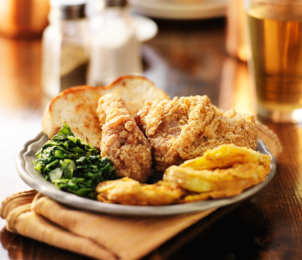 A plate of fried chicken, collards, bread, and fried green tomatoes similar to soul food meals you can find at some restaurants in Topeka. 