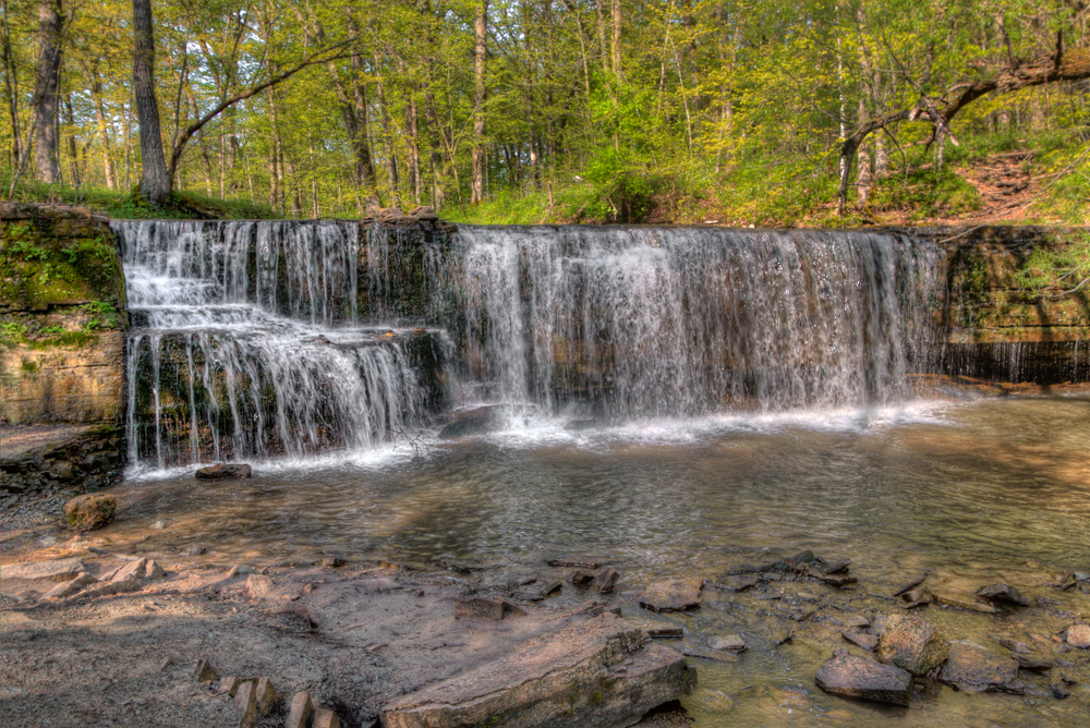 The short Hidden Falls falling into a rocky pool in a forest seen while hiking in Minnesota.