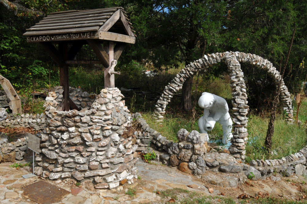 One of the sculptures at Larry Baggett's Trail of Tears Memorial featuring a stone wishing well and a white, stone figure.