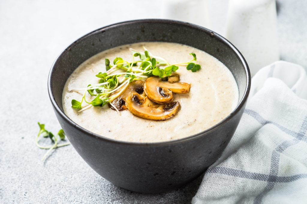 Mushroom Soup in craft bowl on light stone table. In an article about restaurants in Lake Geneva. 