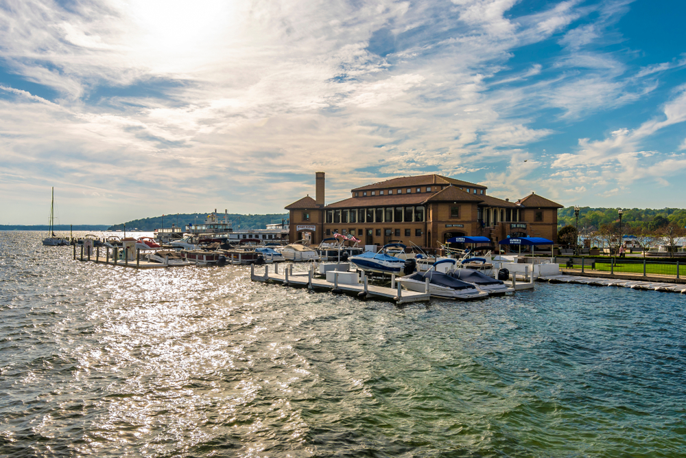 Boats lined up on the dock in Lake Geneva. There is a large building on the  shore behind them.  This is an article about restaurants in Lake Geneva 