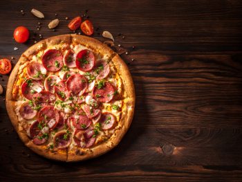 pizza with ham, bacon, salami, and garlic on a wooden table restaurants in sandusky ohio