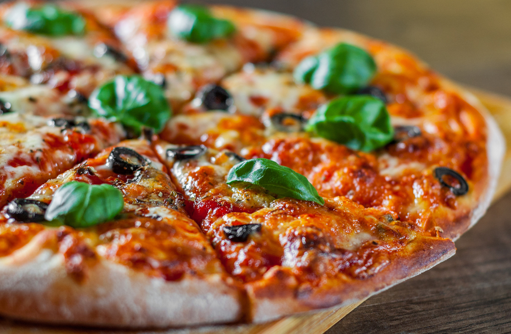 Pizza on wooden board close up. With cheese, olives and basil.  