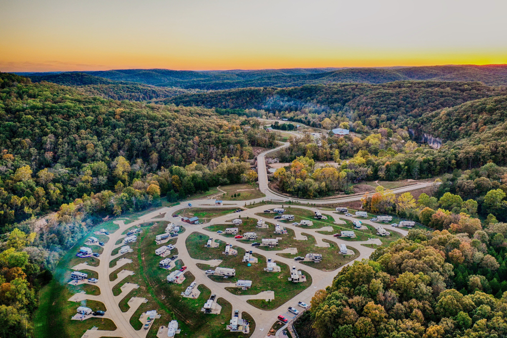 An aerial view of a large RV park surrounded by woods. 
