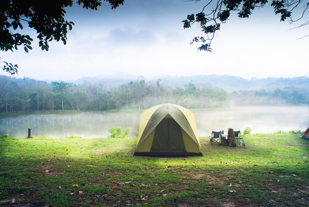 A green tent on the side of a lake with fog on it, one of the best places for camping in Kansas. 