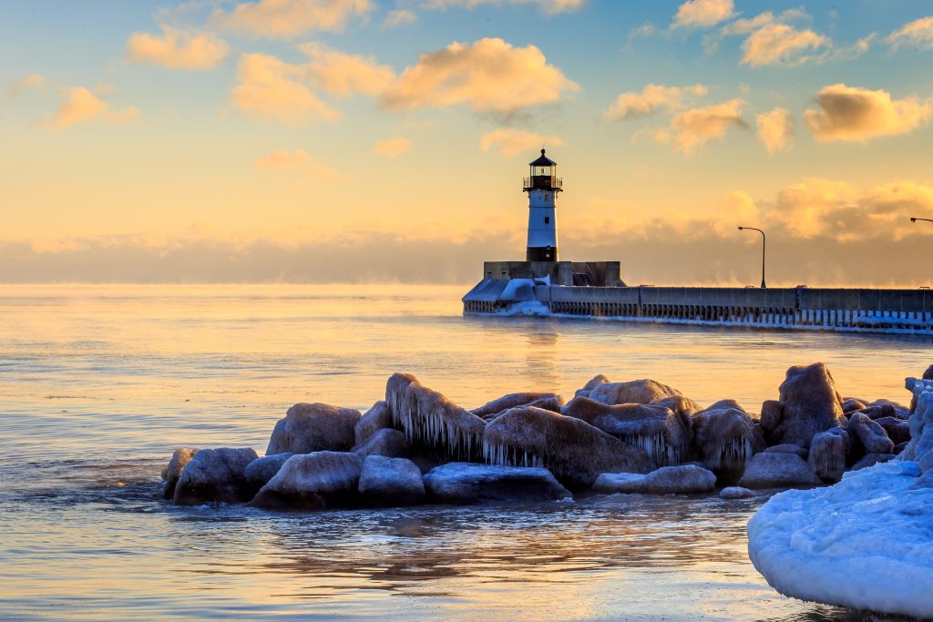 White lighthouse at end of metal pier with large rocks and snow in foreground, sunset sky in background.
Attraction in Duluth Minnesota