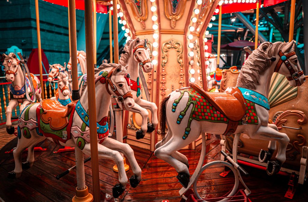 Wooden white horses wearing very colorful blankets and saddles part of merry-go-round one of the fun things to do in Sandusky OH.
