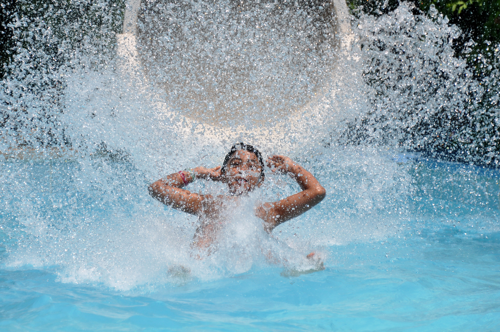 Young boy splashing into the water from a water slide in an article about things to do in Geneva 