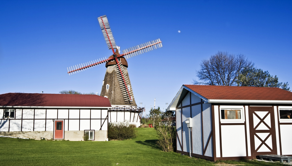 Two red and white houses with a windmill behind them