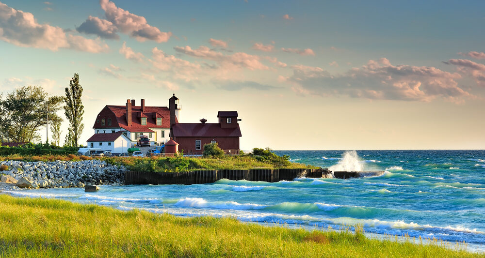 white lighthouse with red roof surrounded by water romantic getaways in Michigan