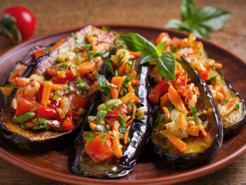 A plate of grilled eggplant with fresh cut vegetables on top of it, similar to what you'll find at one of the best restaurants in Grand Rapids.
