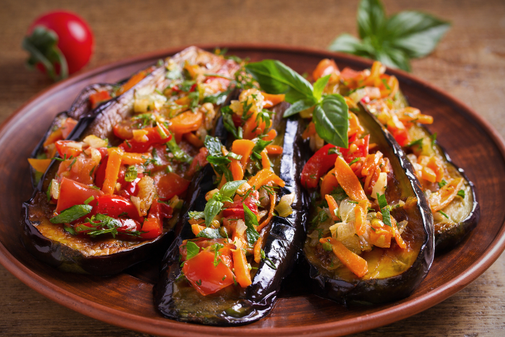 A plate of grilled eggplant with fresh cut vegetables on top of it, similar to what you'll find at one of the best restaurants in Grand Rapids.
