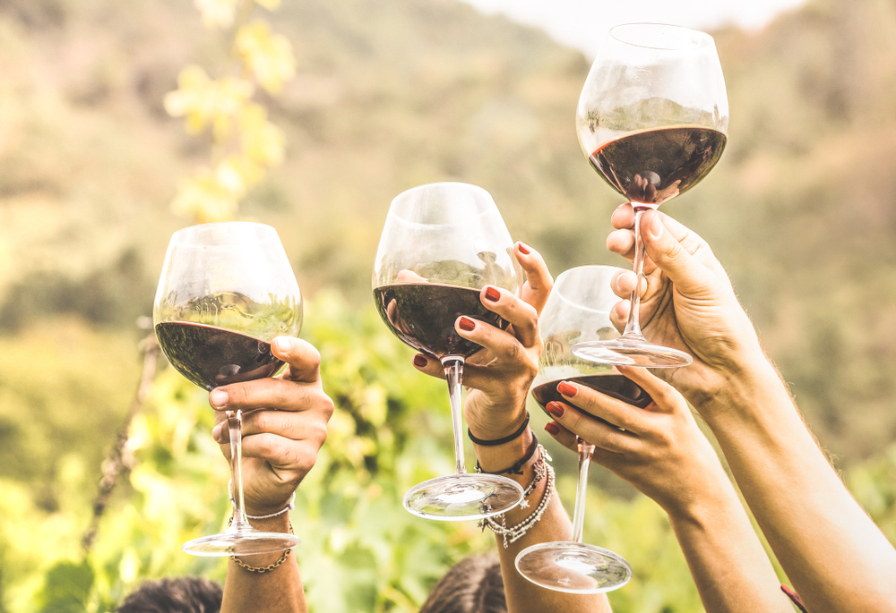 4 white hands holding up glasses of red wine at fun wineries in Ohio