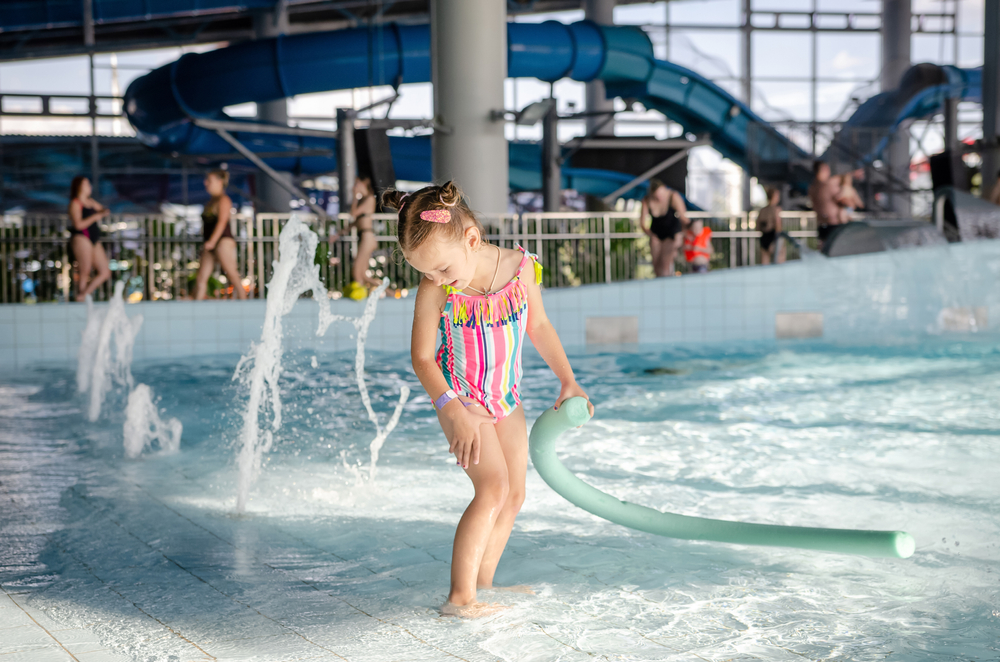 A child playing in a splash area in an indoor waterpark, one of the best things to do in Ohio with kids. 
