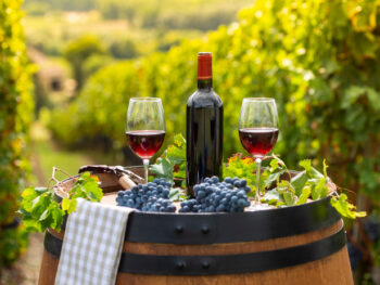 Bottle of red wine sitting on barrel with two glasses with wine and food to taste at wineries in Ohio