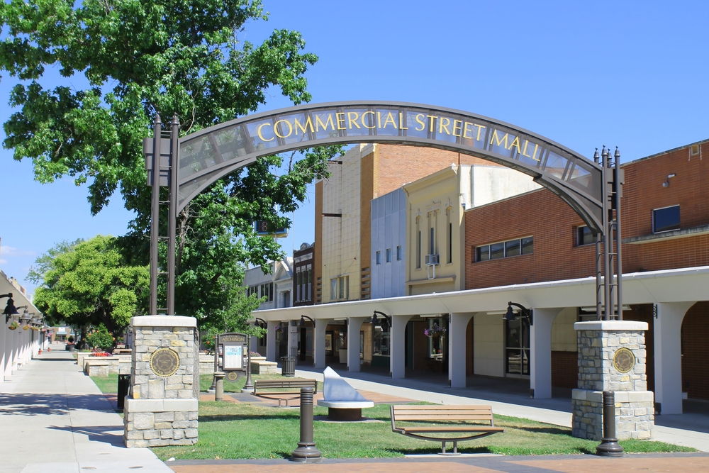 Arched sign saying "Commercial Street Mall" over a town green with shops on the side.