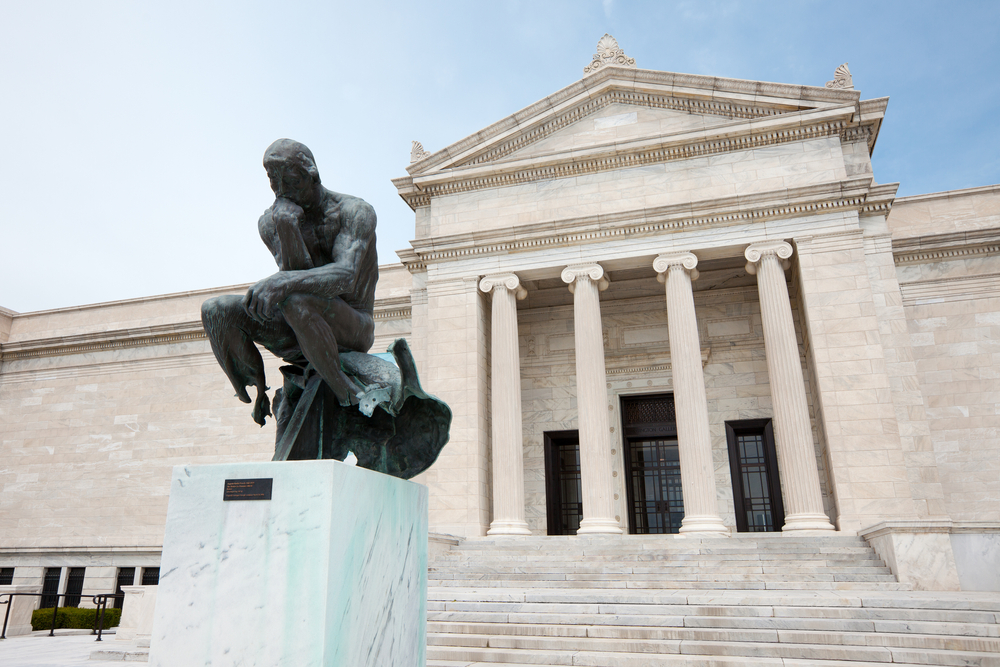 Copy of Rodin's "Thinker" in front of the pillared, marble facade of the Cleveland Museum of Art.