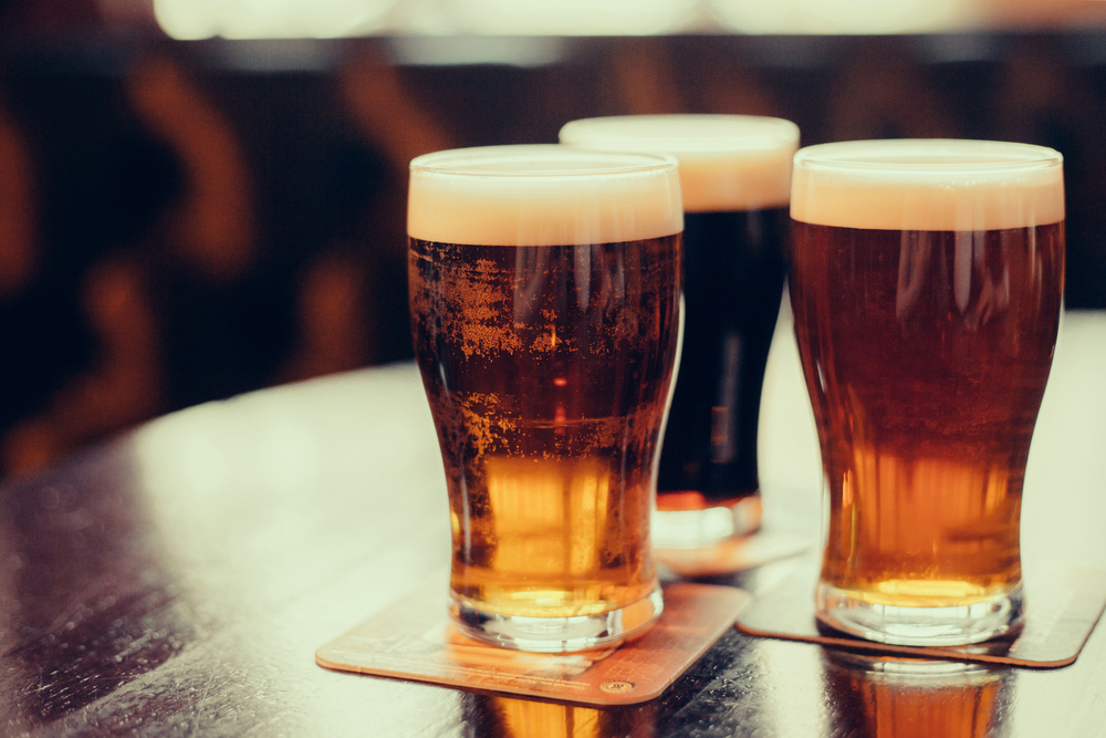 Three glasses of beer sit on a pub table.