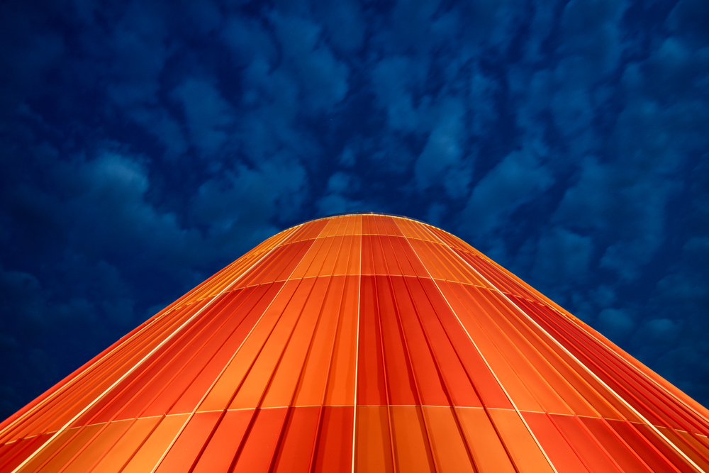 View looking up the Delta College Planetarium at night with the building lit up orange.