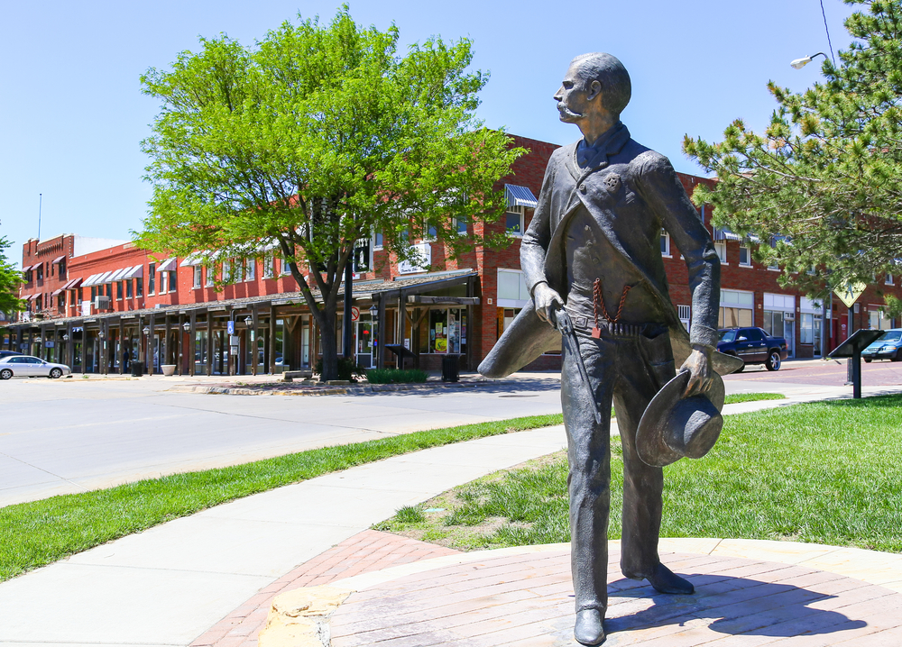 A statue of a frontiersman in front of the historic area of Dodge City.