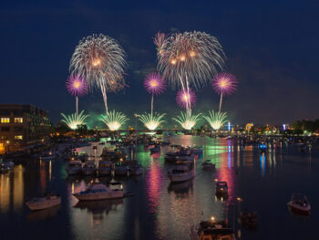 fireworks against dark night with boats and gleaming water in foreground things to do in Bay City MI