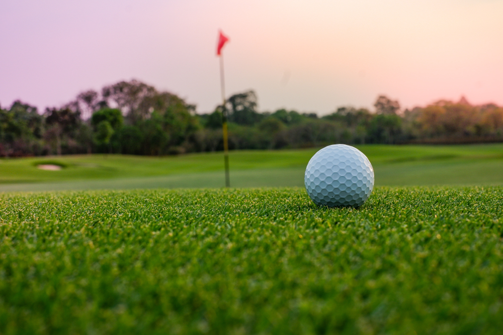 A golf ball sits on a green at sunset at Bay County Golf Course, one of the best things to do in Bay City, MI.