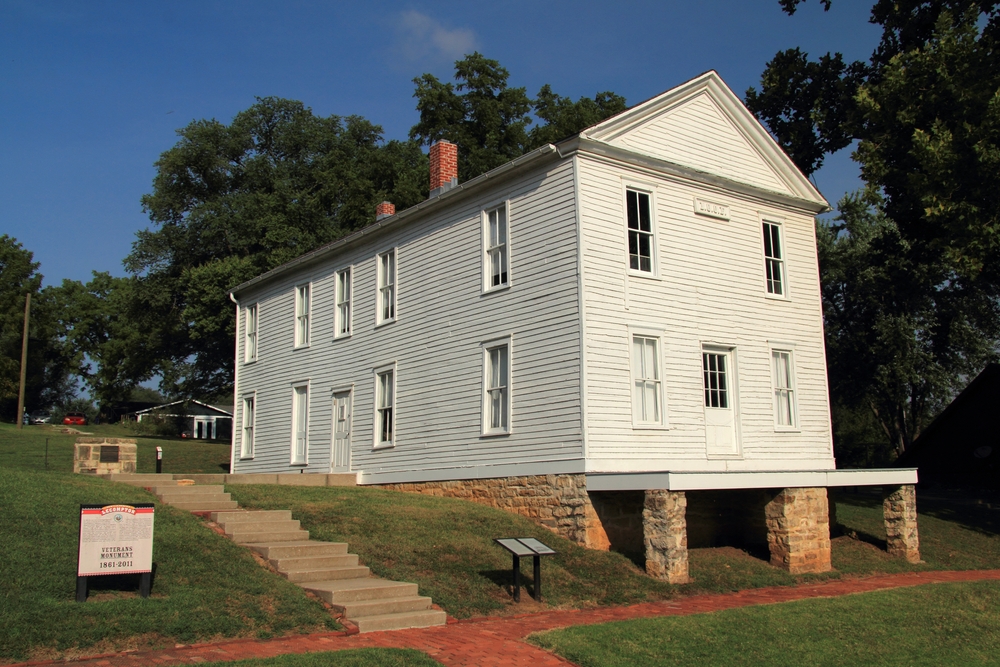 A historic, white wood house next to trees in Lecompton, one of the best small towns in Kansas.